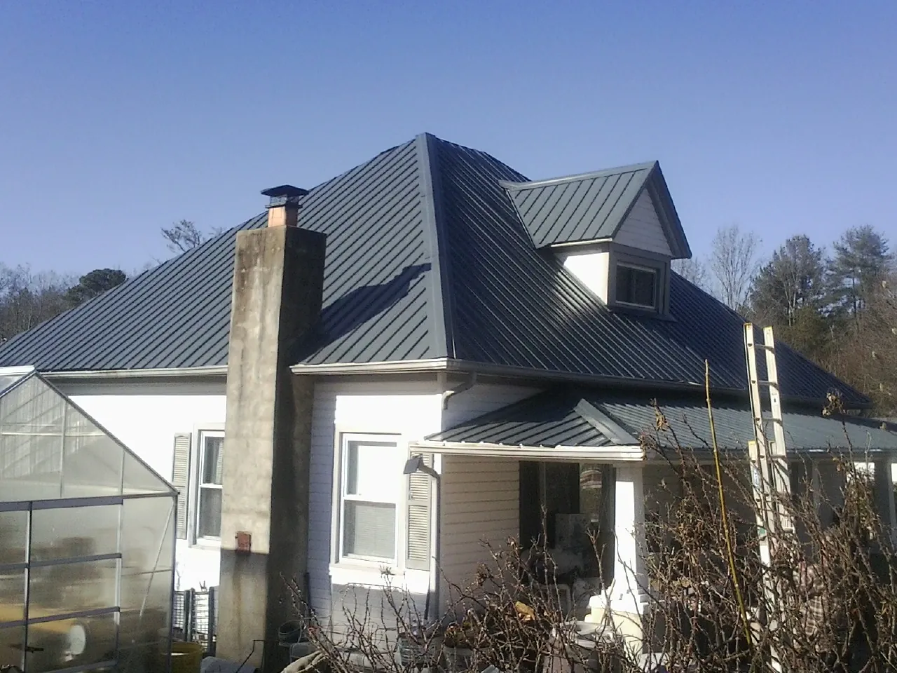 Dark blue standing seam metal roof on a white farmhouse with dormer — Slate & Tile Roof Repair by Roofing Brothers in Hatton