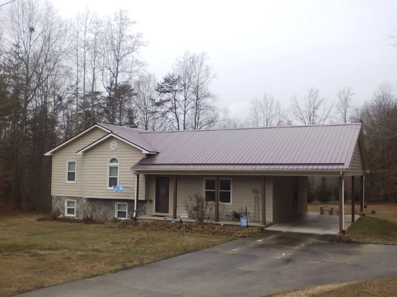 Burgundy metal roof on a tan split level home with an attached carport in Hatton
