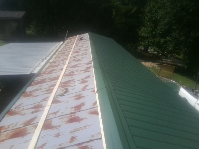 Old rusted panels beside newly installed green metal roofing — Wind Damage Roof Repair by Roofing Brothers in Hatton