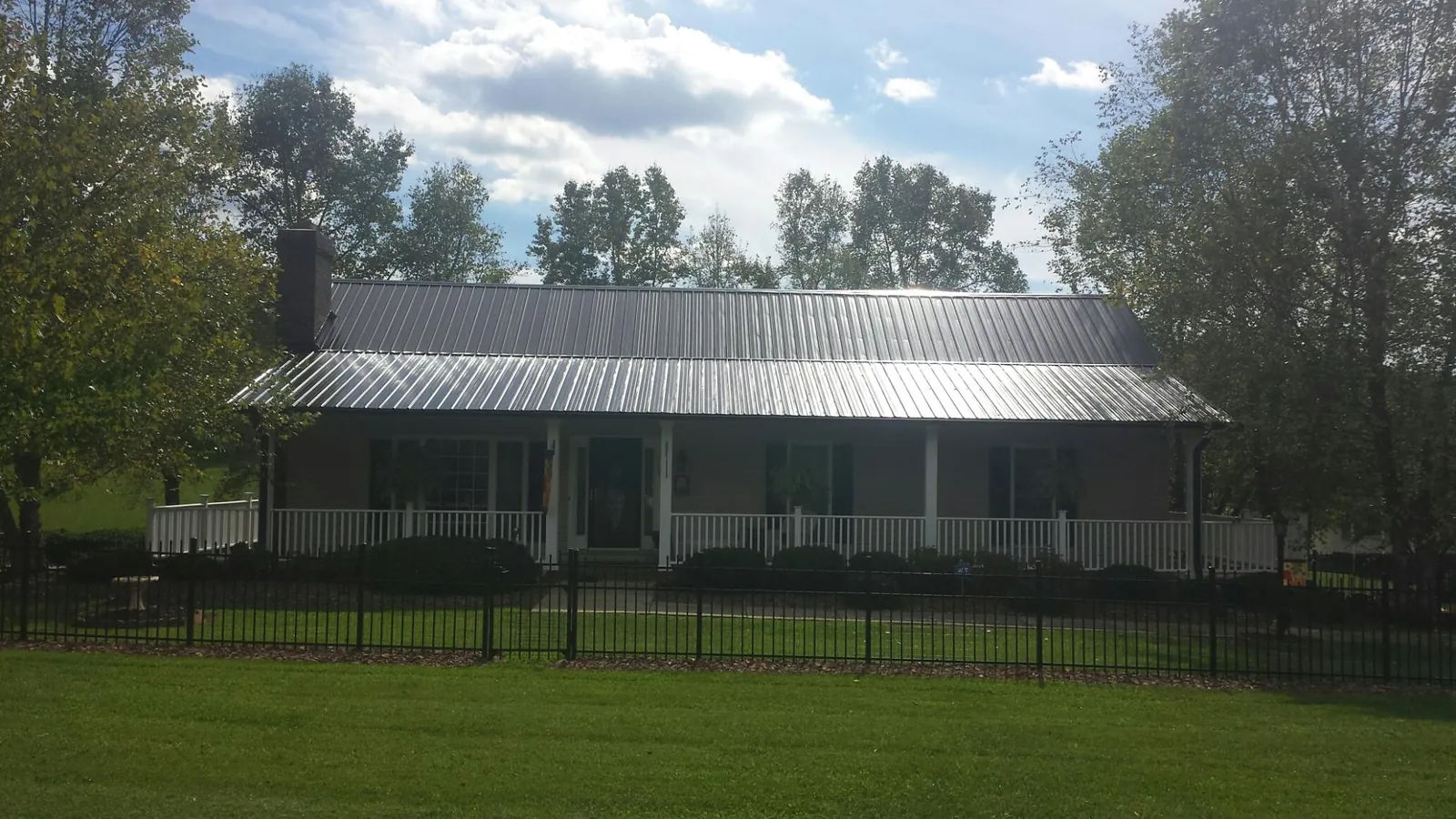 Gray metal roof on a brick ranch with a full width front porch — Gutter Guard Installation work by our crew in Hatton