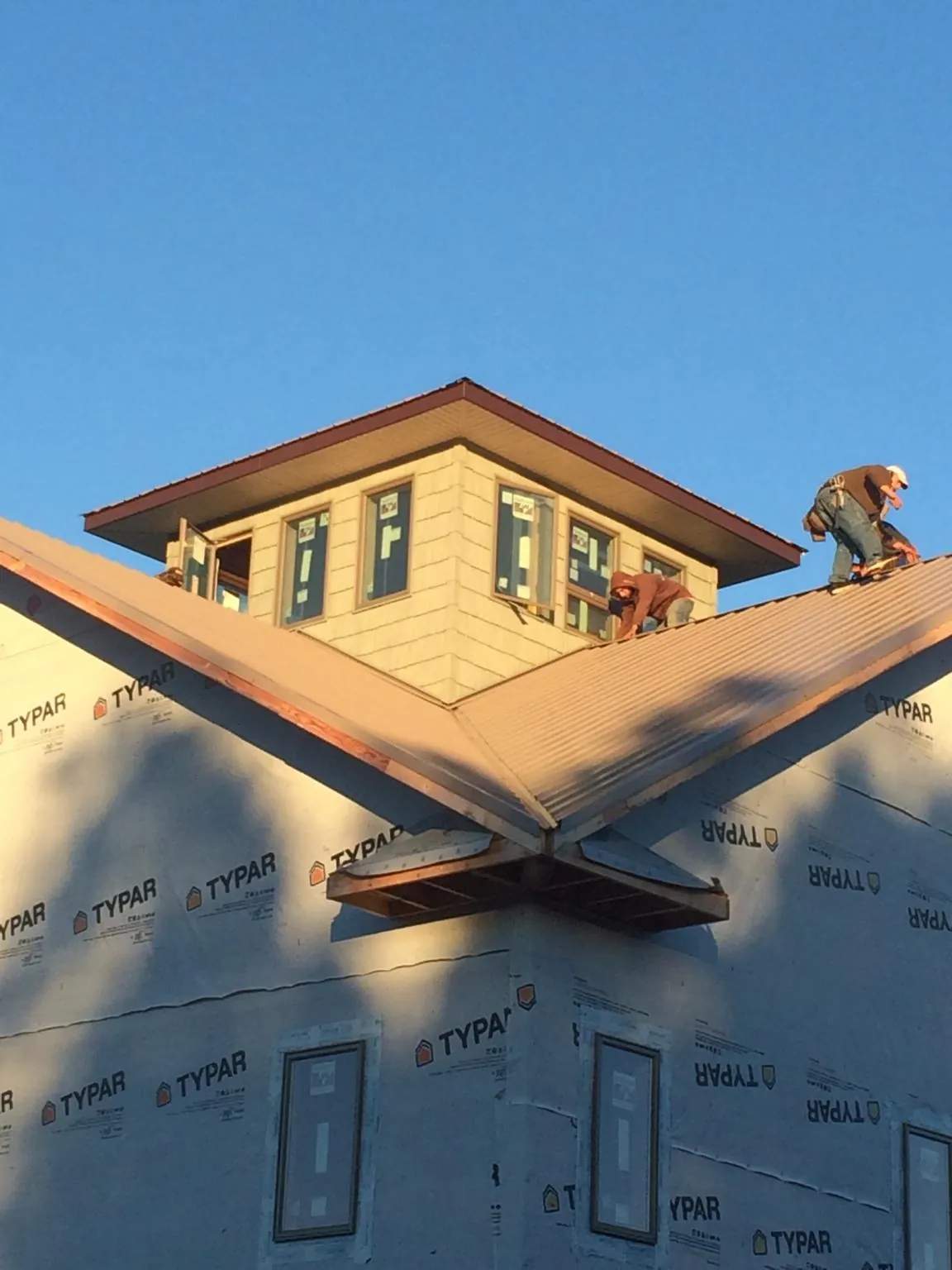Roofers working around a rooftop cupola on a new metal roof at sunset — Roof Waterproofing in Hatton by Roofing Brothers